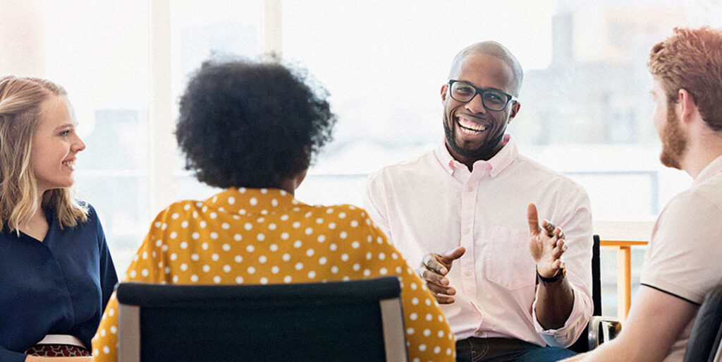 Colleagues sat around a table in a meeting. All smiling.