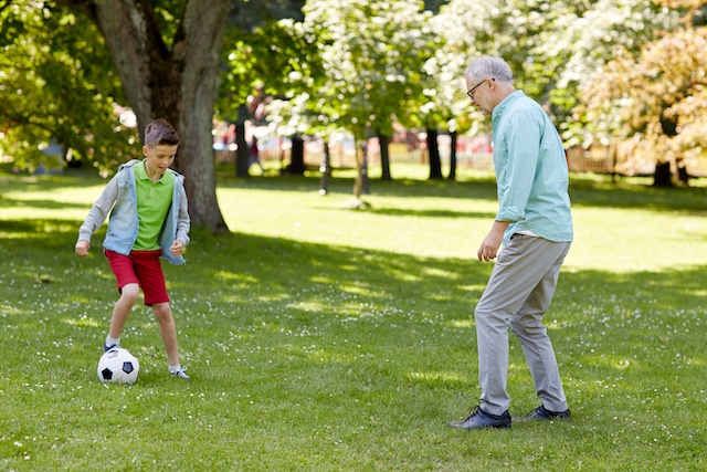 grandfather playing football with his grandson in the park.