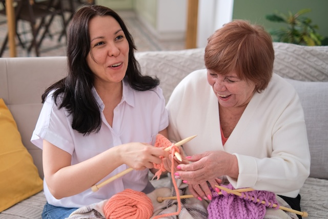 Mother and Daughter Bonding over Knitting. Woman Teaches her Adult Daughter the Art of Knitting.